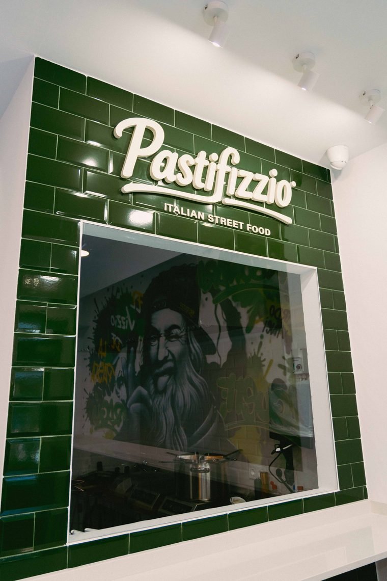 La cocina a la vista de Pastifizzio: ventana al obrador con el logo Italian Street Food